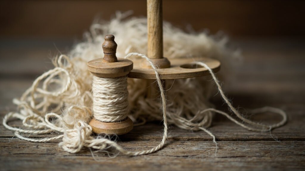 Bobine, quenouille et fibres de lin sur bois.
