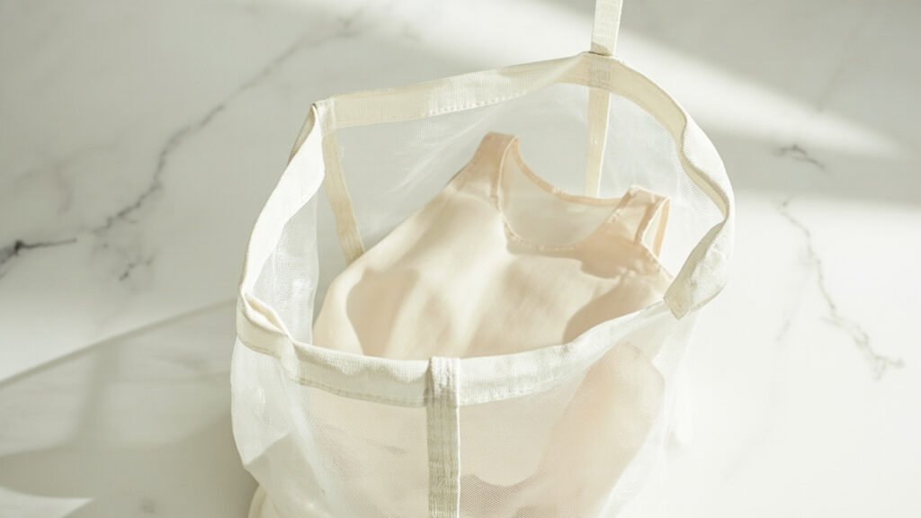 Camisole de soie ivoire pliée dans un filet de lavage.