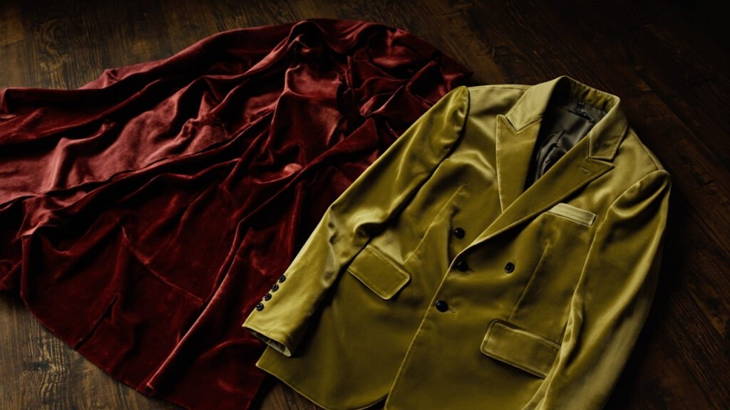 Capeline velours cramoisi antique et blazer vert moderne sur noyer.