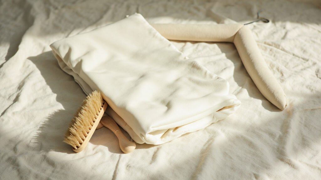 Couvre-lit satin de laine ivoire plié avec brosse et cintre.