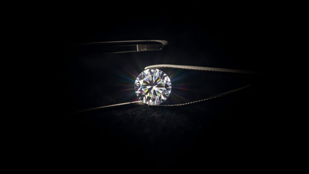Diamant tenu par une pince, loupe posée sur velours noir.