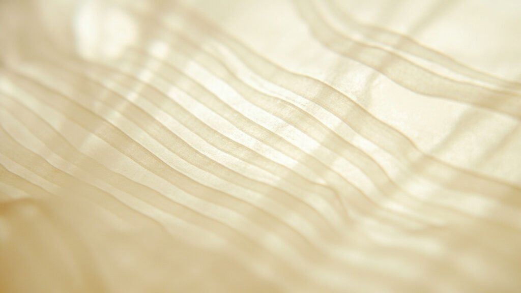 Gros plan du tissage satin, longs flotteurs brillants sous lumière rasante.
