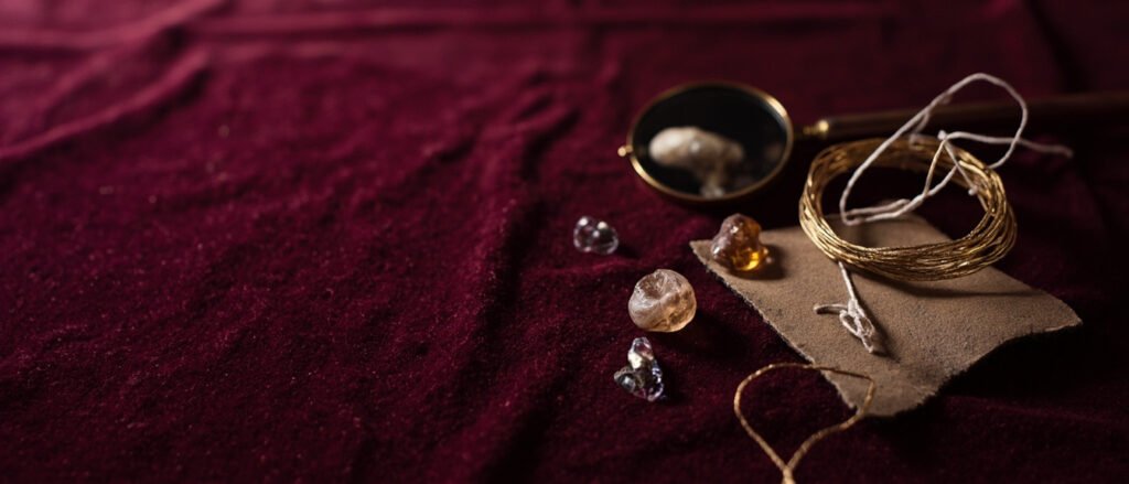 Héritage joaillier : loupe, cabochons, fils d'or, soie et velours bordeaux.