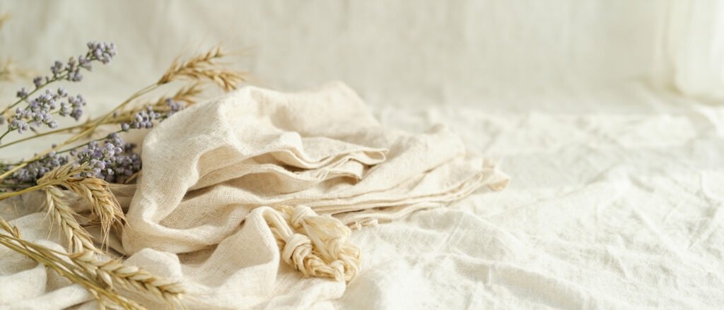 Lin bleu, fibres brutes crème et tissu écru sur bannière panoramique.