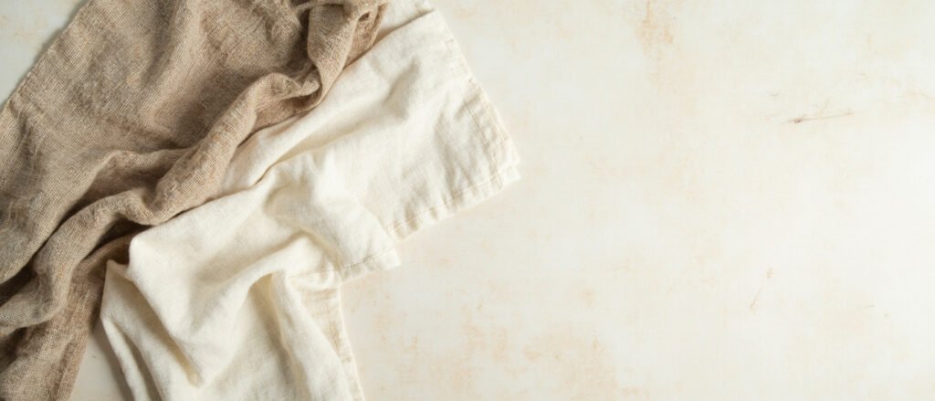 Lin brut texturé à côté de coton lisse et crème, contraste des fibres.
