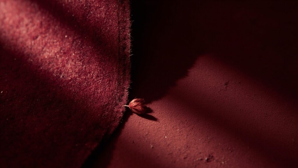 Macro: velours bordeaux, mi-écrasé mi-droit, fibre isolée.