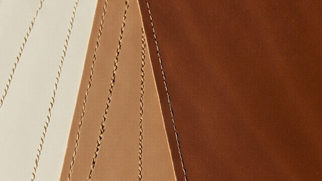 Panneaux de cuir superposés présentant différents types de coutures artisanales.