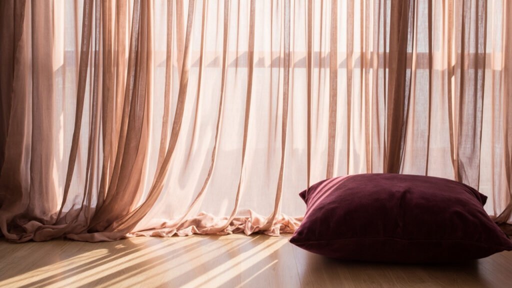 Rideau de soie rose poudré, plis lumineux sur parquet chêne clair.