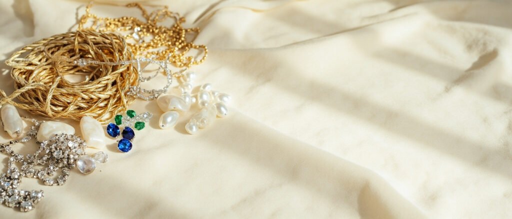 Satin ivoire, strass fantaisie, chaînes d'or et pierres précieuses étalées.