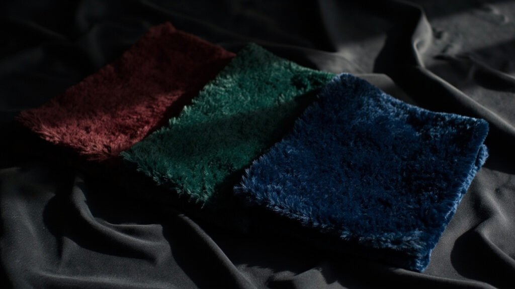 Trois échantillons de velours pliés en éventail sur satin foncé.