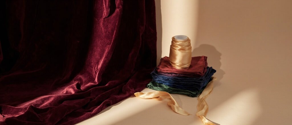 Velours bourgogne drapé en plis, échantillons de teintes jewel, lumière rasante.