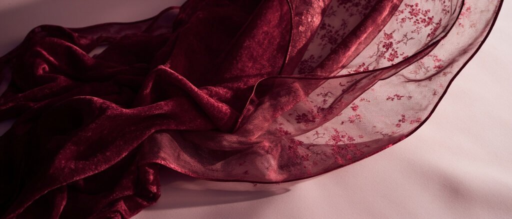 Velours dévoré soie bordeaux, motifs transparents et pile dense, lumière douce.