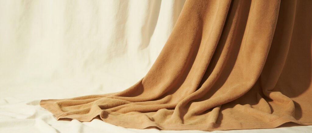 Drapé de cachemire double face camel, pli révélant la surface réversible veloutée.