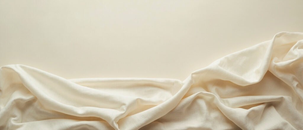 Soie recyclée écrue drapée, plis ondulés révélant la trame irrégulière.